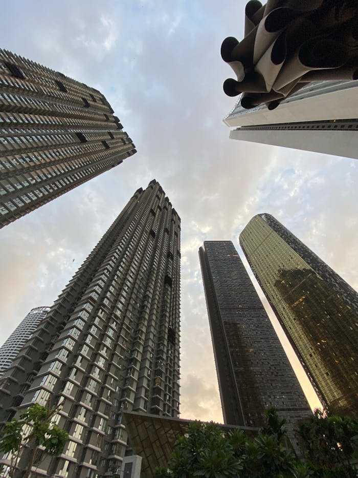 Dramatic low-angle view of skyscrapers against a cloudy sky in Mumbai, India.